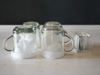 Freshly cleaned glass mugs, inverted with paper towels, ready for new customers at a vibrant cafe