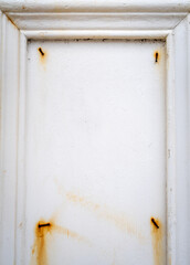 Rusty nails on a white wooden frame with peeling paint