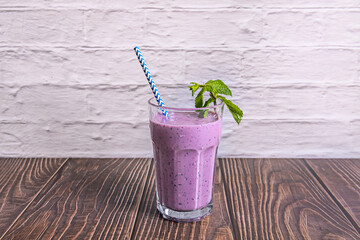 Center-shot: Blueberry and vanilla smoothie in a clear glass, surrounded by fresh blueberries and...