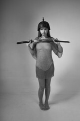 Warrior woman in chainmail and medieval Asian helmet holding traditional Japanese sword katana on...