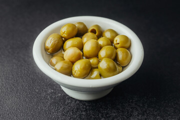 Green olives in ceramic bowl  on a dark background