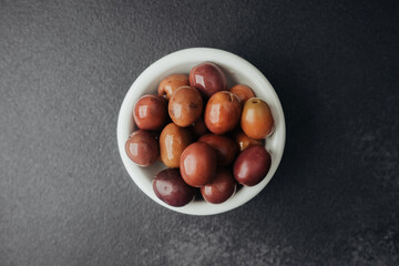 Bowl with red kalamata olives on black textured table