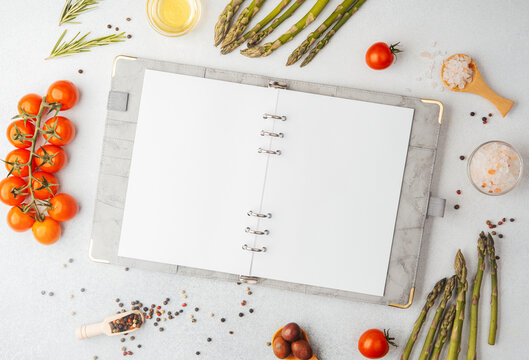 Blank recipe book with cooking ingredients on white background