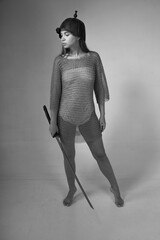 Warrior woman in chainmail and medieval Asian helmet holding traditional Japanese sword katana on...