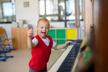 Boy with Down syndrome playing piano at school.