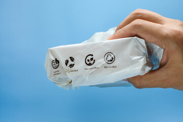 A human hand gripping a product wrapped in white packaging, featuring clear eco friendly icons. Suitable for sustainability, eco products, green marketing, zero-waste lifestyle, and circular economy