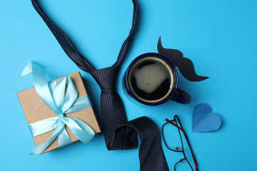 Father's Day. composition with gift box, glasses, cup of coffee and tie on blue background.
