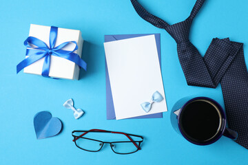 Father's Day. composition with gift box, glasses, cup of coffee and tie on blue background.
