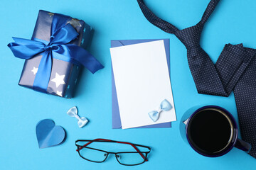Father's Day. composition with gift box, glasses, cup of coffee and tie on blue background.
