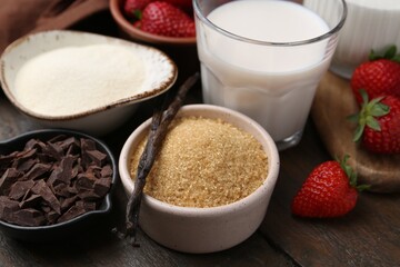 Different ingredients for panna cotta. Milk, sugar, vanilla, chocolate and strawberries on wooden table, closeup