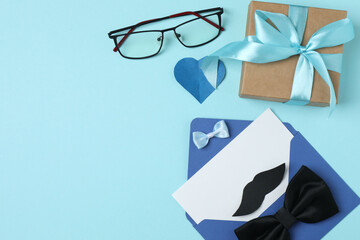 Father's Day. composition with gift box, glasses, cup of coffee and tie on blue background.
