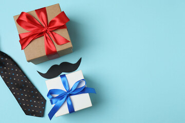 Father's Day. composition with gift box, glasses, cup of coffee and tie on blue background.

