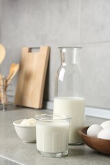 Different dairy products and eggs on gray textured table in kitchen
