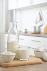 Different dairy products and eggs on wooden table in kitchen