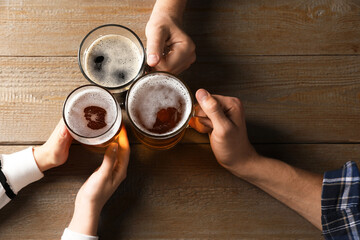 Friends with glasses of beer at wooden table, top view