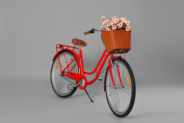 Bicycle with basket of beautiful flowers on grey background
