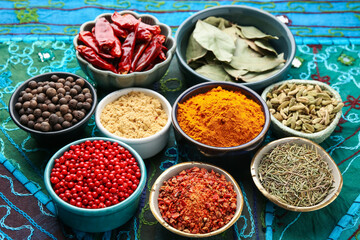 Many different aromatic spices in bowls on table with cloth, closeup