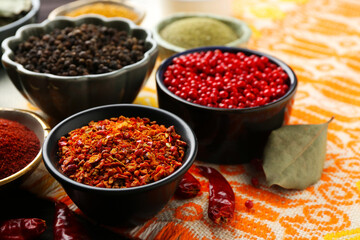 Different aromatic spices on orange tablecloth, closeup