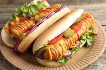 Tasty hot dogs with vegetables, mustard and ketchup on wooden table, closeup