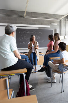 Chemistry teacher explaining chemical formulas to students in classroom