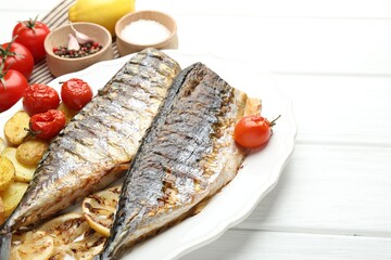 Homemade seafood dish. Tasty roasted mackerels with spices, tomatoes and potatoes on white wooden table, closeup. Space for text