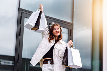 Young woman celebrates successful shopping spree with multiple bags in stylish outfit
