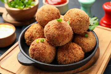 Delicious fried croquette balls with green onion on grey table, closeup
