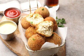 Delicious fried croquette balls and sauces on grey textured table, closeup