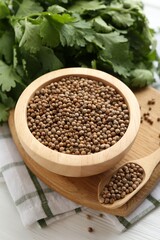 Coriander seeds and fresh cilantro on white wooden table, closeup
