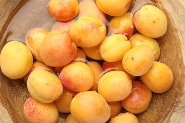 Fresh ripe apricots in wooden bowl with water, top view