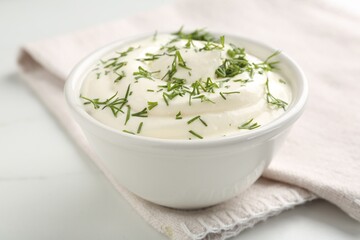 Delicious yogurt in bowl and dill on white marble table, closeup