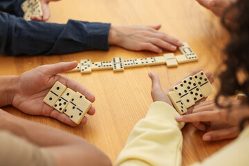 Friends playing dominoes at wooden table, closeup