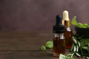 Bottles of aromatic essential oils and herbs on wooden table against brown background, closeup....