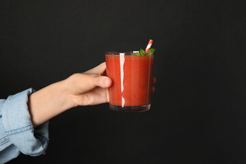 Superfood. Woman with glass of tasty smoothie against black background, closeup. Space for text
