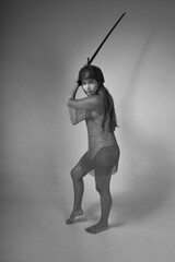 Full length black and white portrait of young warrior woman in chainmail and original medieval...