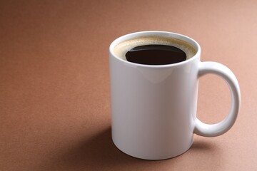 Tasty coffee in cup on brown table, closeup. Space for text