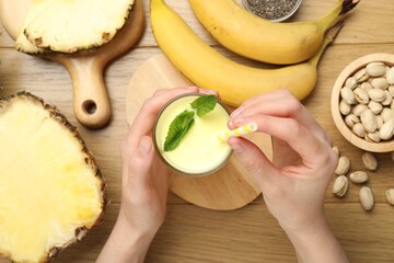 Superfood. Woman with tasty smoothie and ingredients at wooden table, top view
