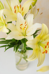 Obraz premium Yellow lilies in glass vase – perfect for natural home decor or minimalist floral stock themes