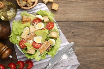 Delicious salad with croutons and ingredients on wooden table, flat lay. Space for text