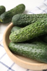 Fresh cucumbers in bowl on white table, closeup