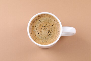 Aromatic coffee in cup on beige background, above view