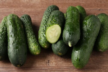 Whole and cut cucumbers on wooden table, closeup
