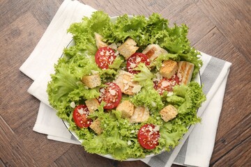 Tasty salad with croutons, tomatoes, cheese and chicken on wooden table, top view