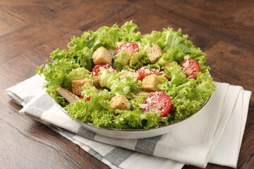 Tasty salad with croutons, tomatoes, cheese and chicken on wooden table, closeup
