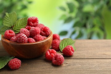 Tasty fresh ripe raspberries and leaves on wooden table, closeup. Space for text