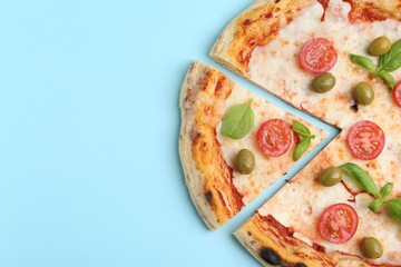 Delicious pizza with tomatoes, basil and olives on light blue background, top view. Space for text