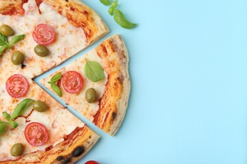 Delicious cut pizza with tomatoes, basil and olives on light blue background, top view. Space for...
