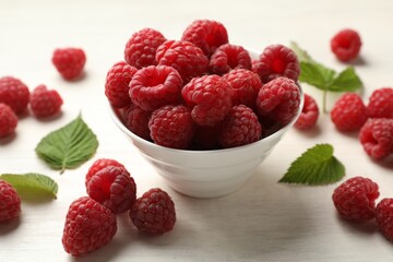 Tasty fresh ripe raspberries and leaves on white wooden table, closeup