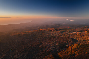 Volcanic landscape of Mount Etna with rugged lava fields, smoke rising from the crater, and...