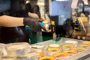 Pastry chef is using a blowtorch to make egg tarts